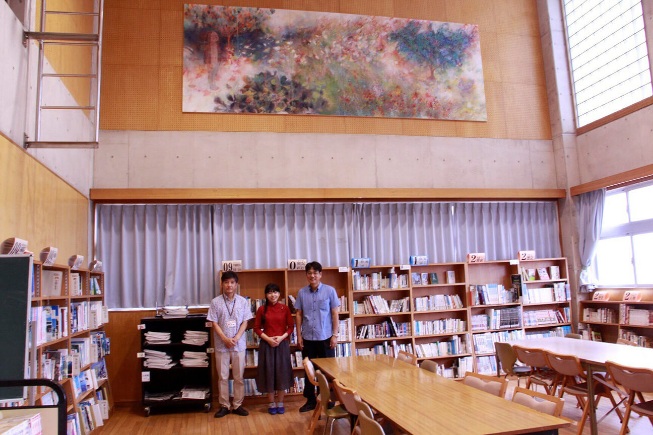 ［写真］設置された作品の下、左から望月教頭、小林さん、松田校長