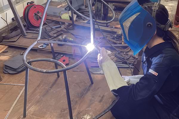 ［写真］溶接作業で椅子を制作している女子学生